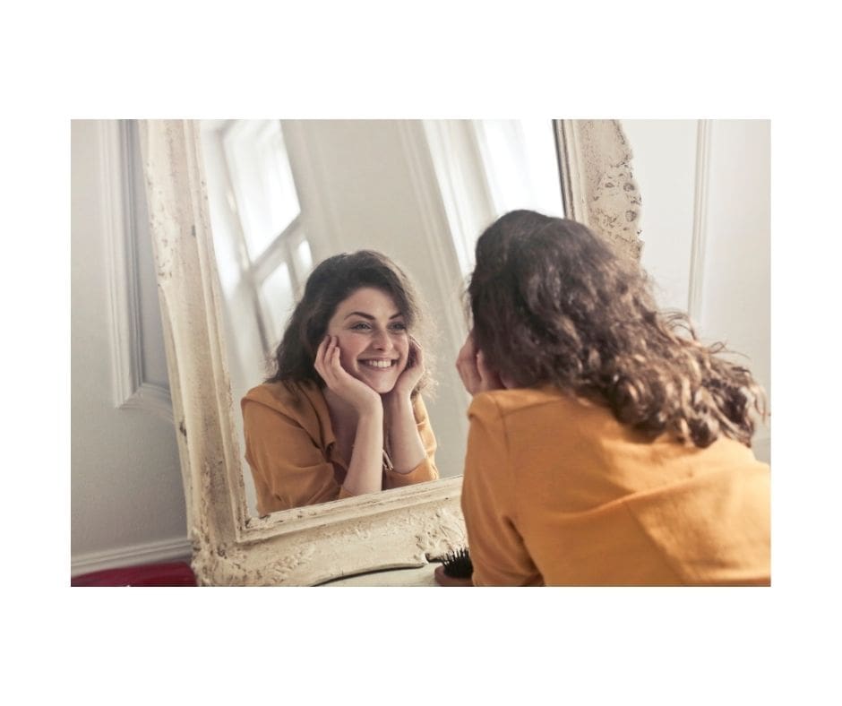 Lady smiling in the mirror to overcoem self-doubt